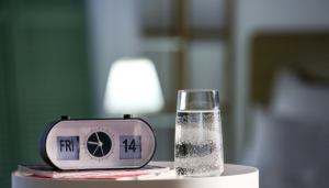 Copo de água em uma mesa de cabeceira, hábito essencial em uma rotina matinal para ter mais disposição.